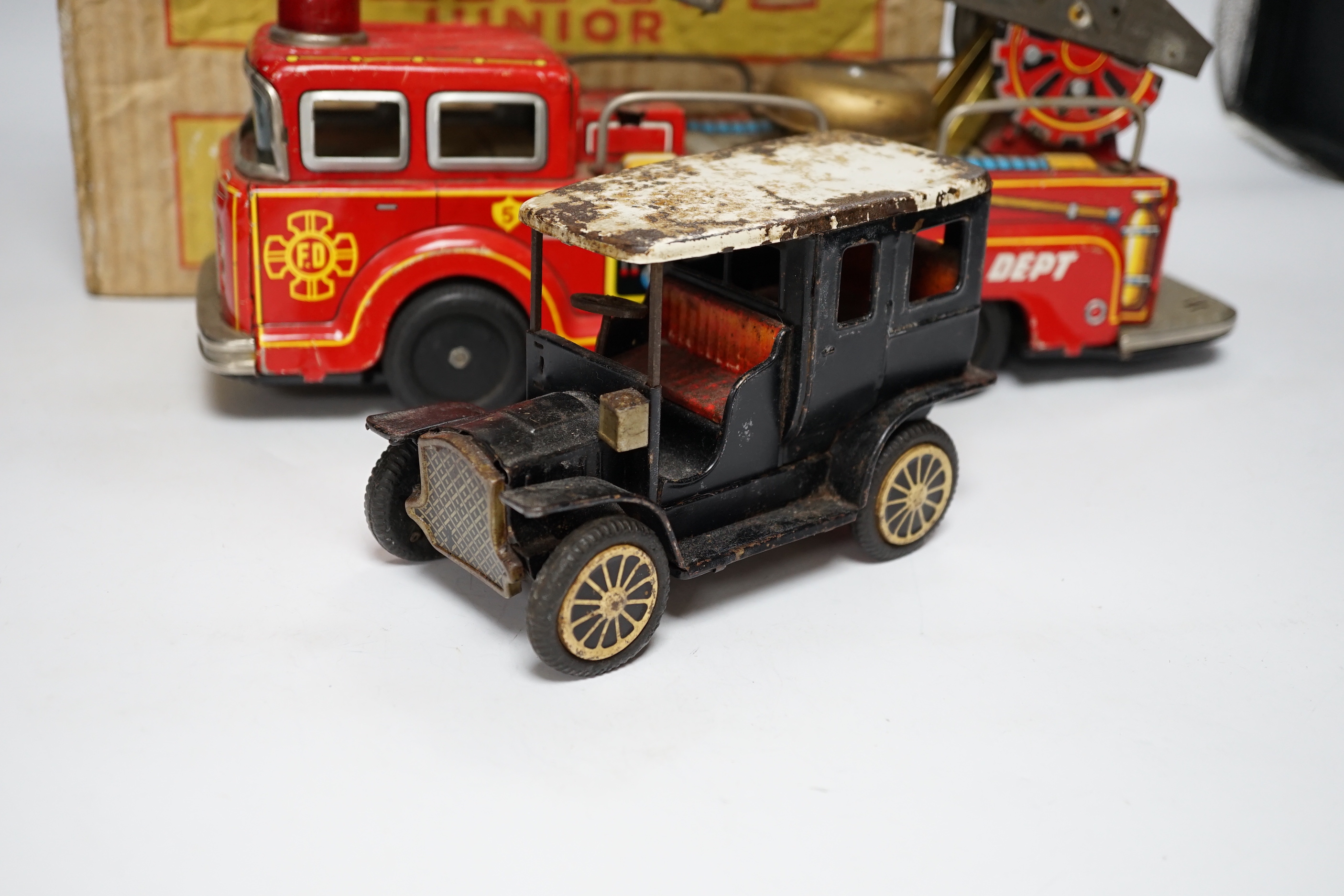 Four tinplate toys; a model of a 1920s taxi, a 1960s German made fire engine, an automaton clown, and a boxed Mettype Junior children’s typewriter